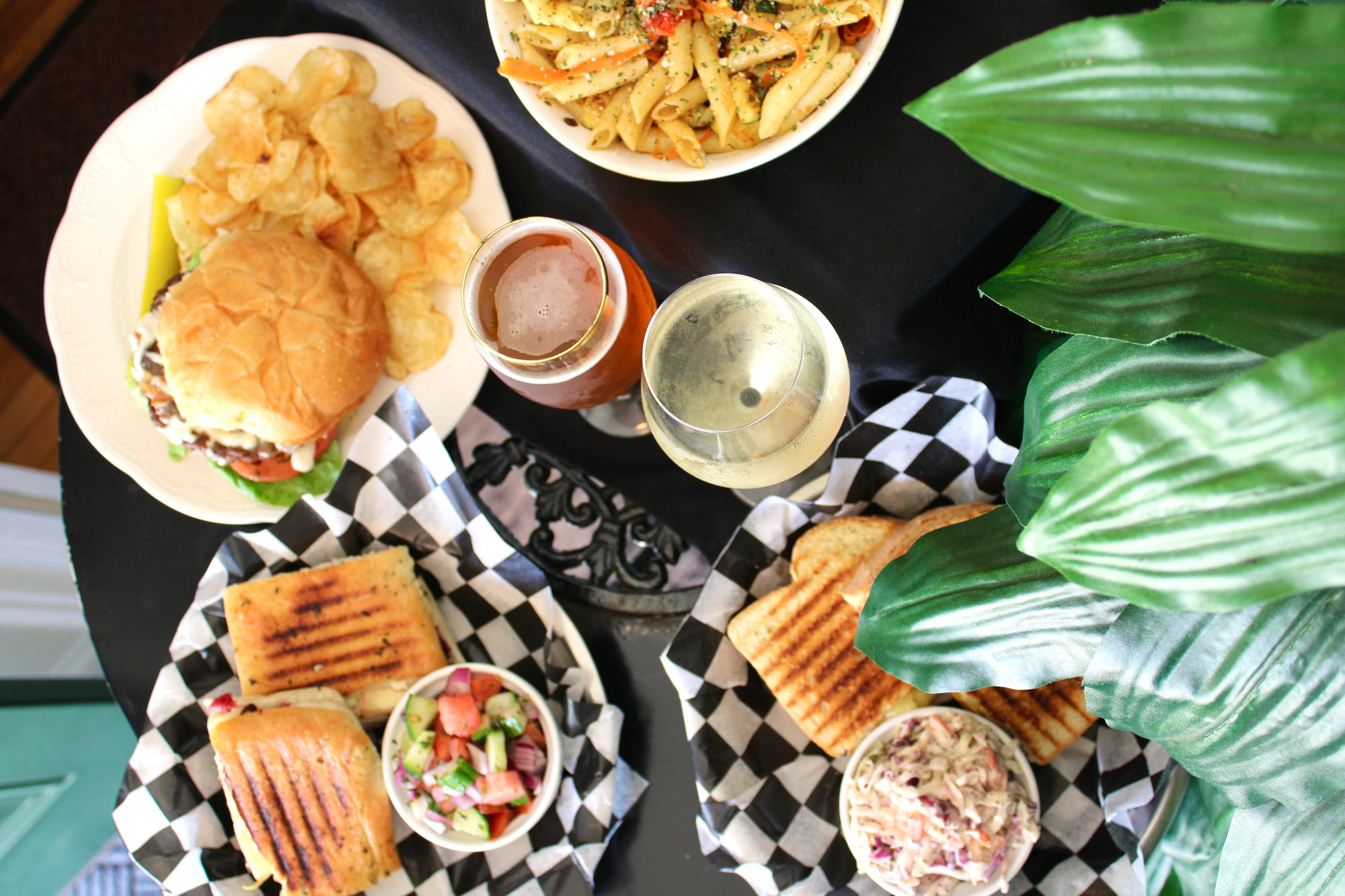 An overhead spread of paninis, a burger, pasta and drinks at Olive's Eatery